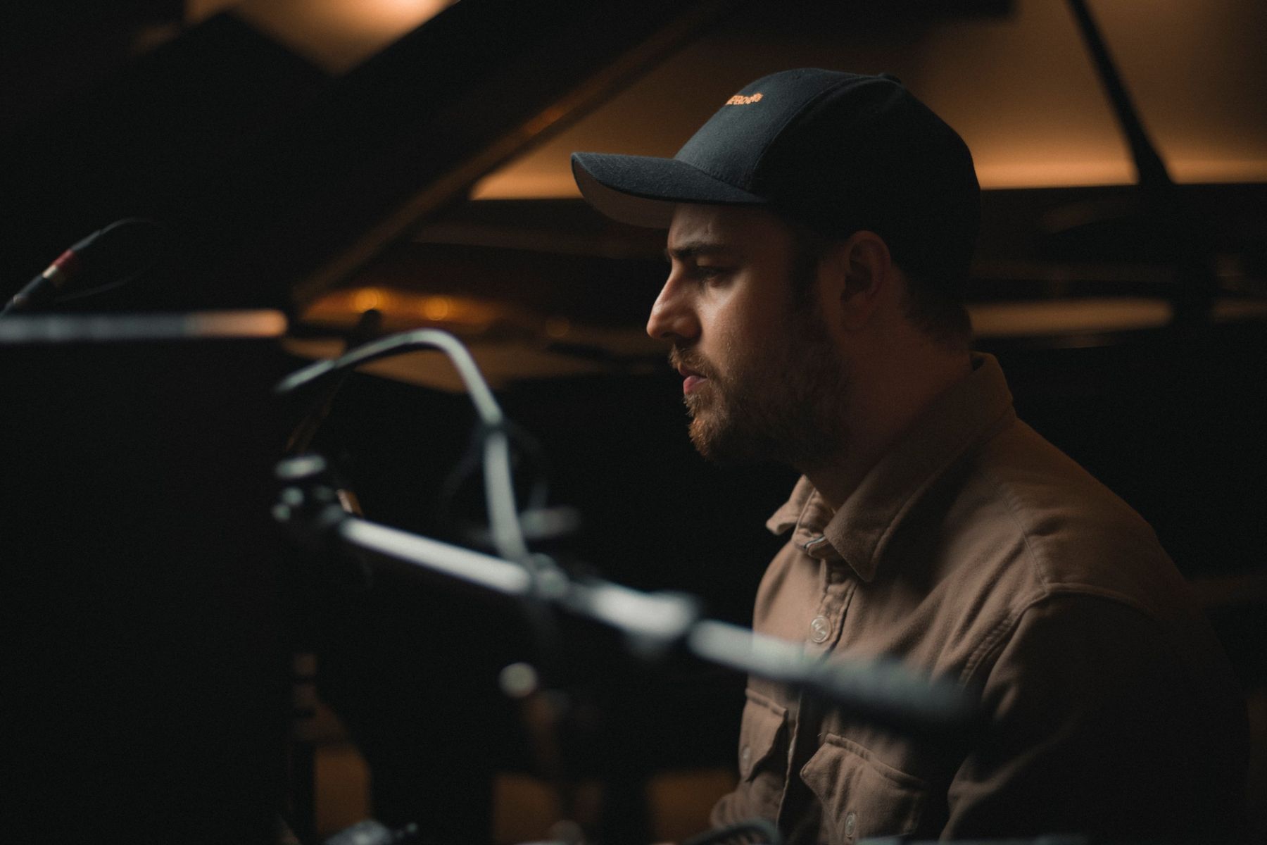 Elliott in profile at a grand piano, the raised lid glowing behind him